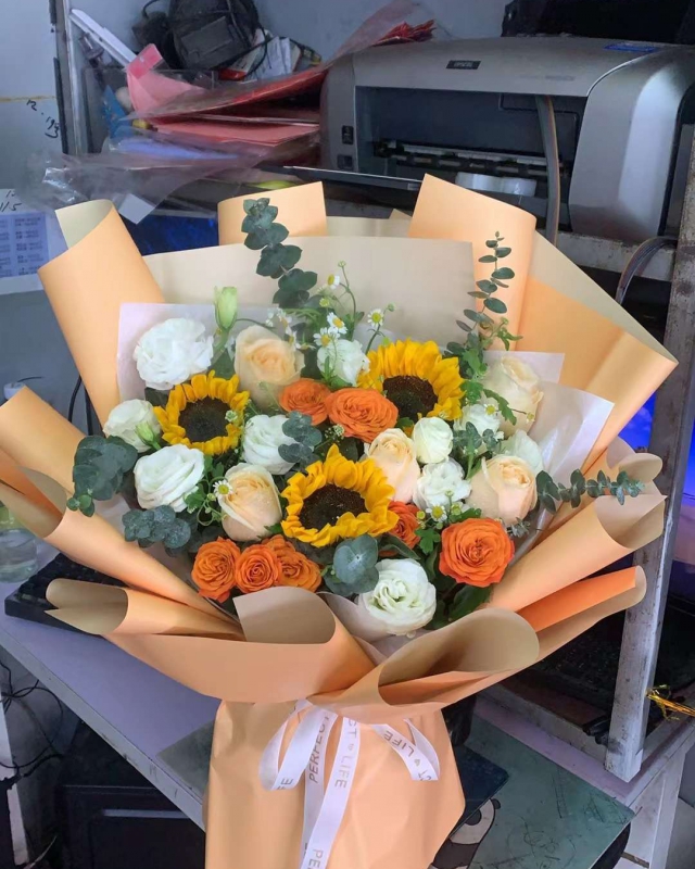 5枝香檳玫瑰，3枝向日葵，3枝橙色多頭玫瑰，洋桔梗+洋甘菊+尤加利搭配，內(nèi)白色牛奶棉，外蜜瓜色歐雅紙